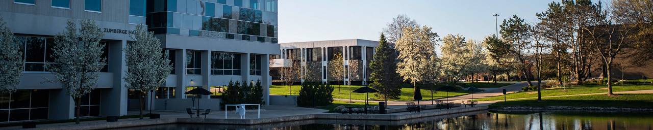 An exterior building view of Zumberge Hall and Lake Superior Hall with blooming spring trees